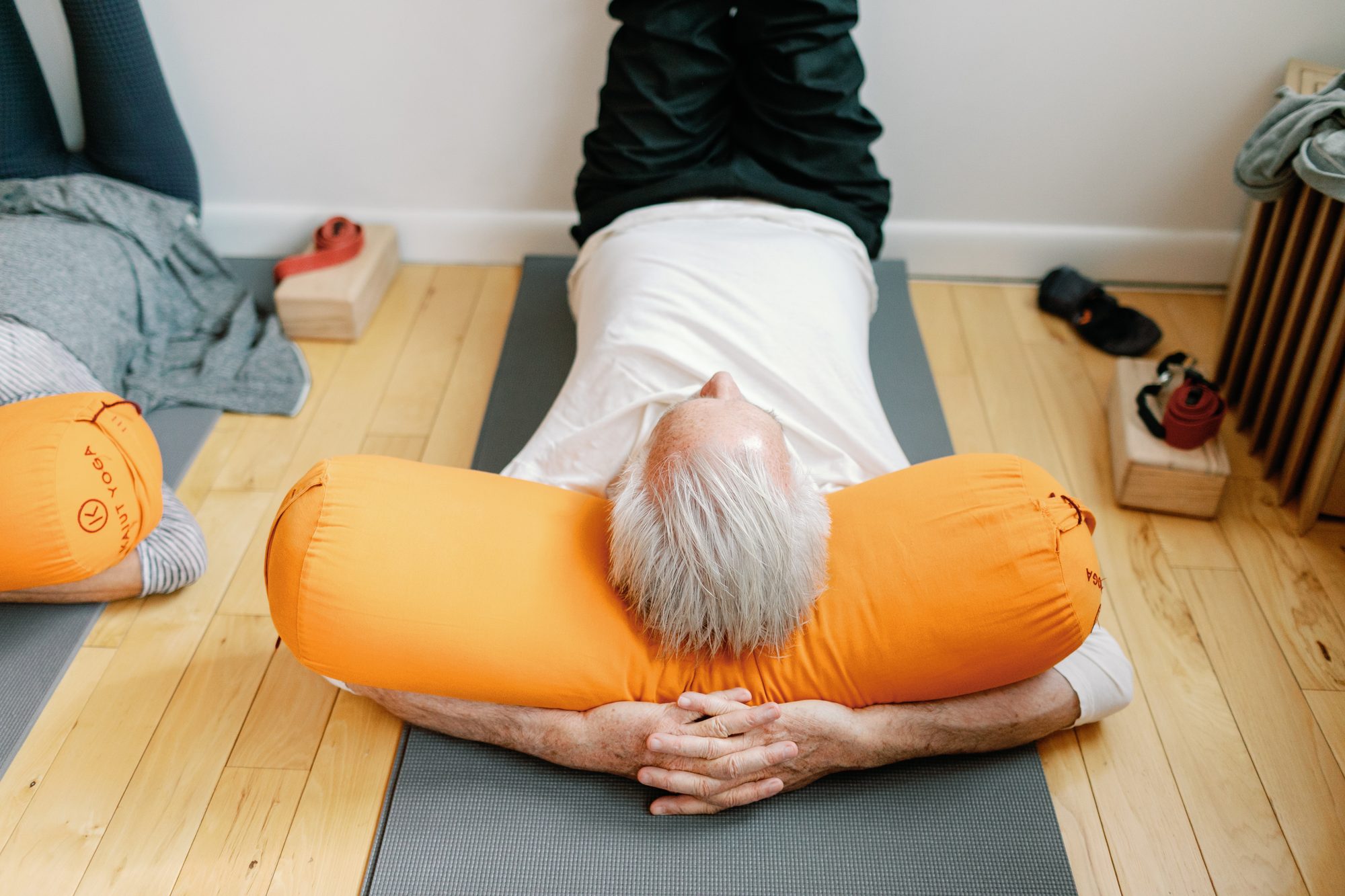 An older student rests over an orange bolster in the South Austin studio